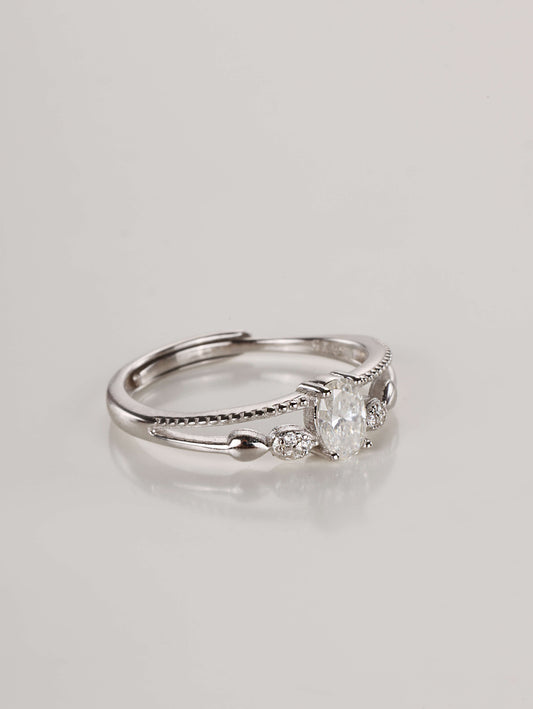 Close-up macro shot of the 925 sterling silver ring highlighting the split-shank double band, delicate milgrain texture, and brilliant oval moissanite stone.