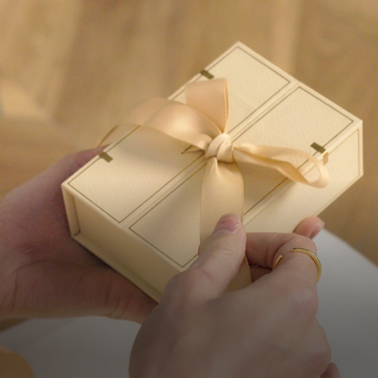 Close-up of a premium white jewellery gift box tied with a silky beige satin bow, ready for gifting