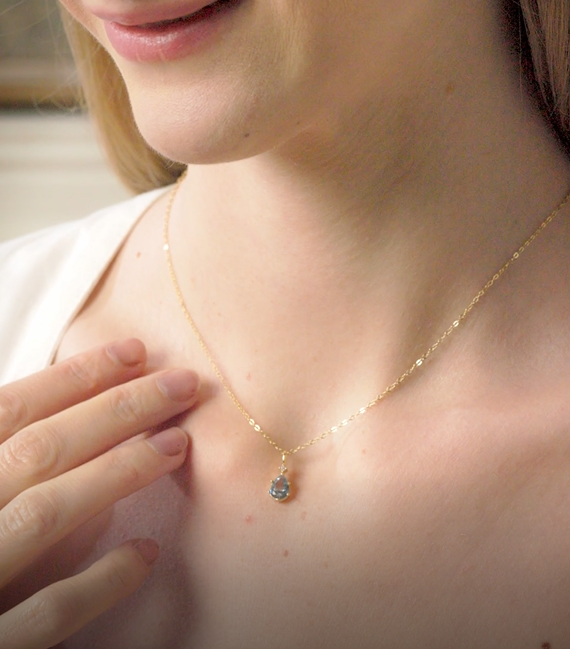 Woman wearing layered 14k gold vermeil pendant necklaces and delicate chains on collarbone. Dialuxé demi-fine jewellery made from recycled sterling silver.