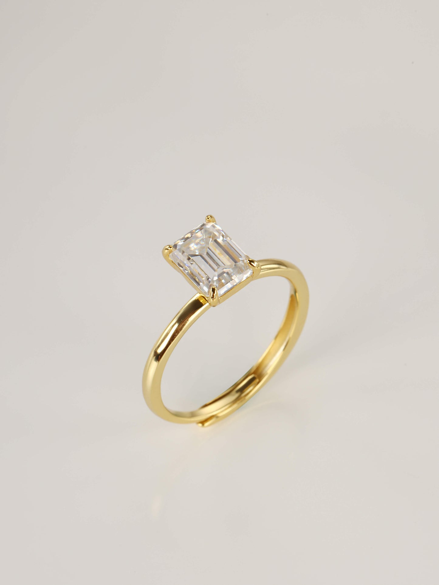 An elegant emerald-cut moissanite solitaire ring resting gracefully beside its signature luxury gift box and protective microfibre pouch.