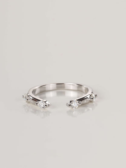 Close-up of a delicate 925 silver open front ring resting on a pale surface, featuring four spaced moissanite stones totalling 0.24ct.