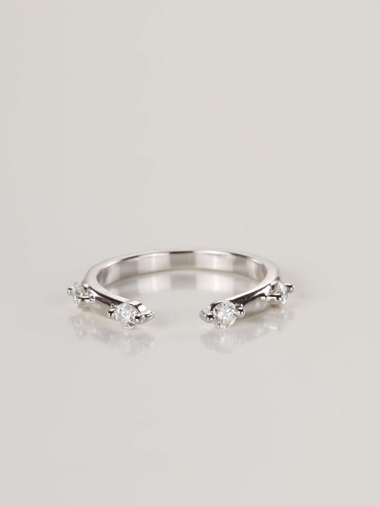Close-up of a delicate 925 silver open front ring resting on a pale surface, featuring four spaced moissanite stones totalling 0.24ct.