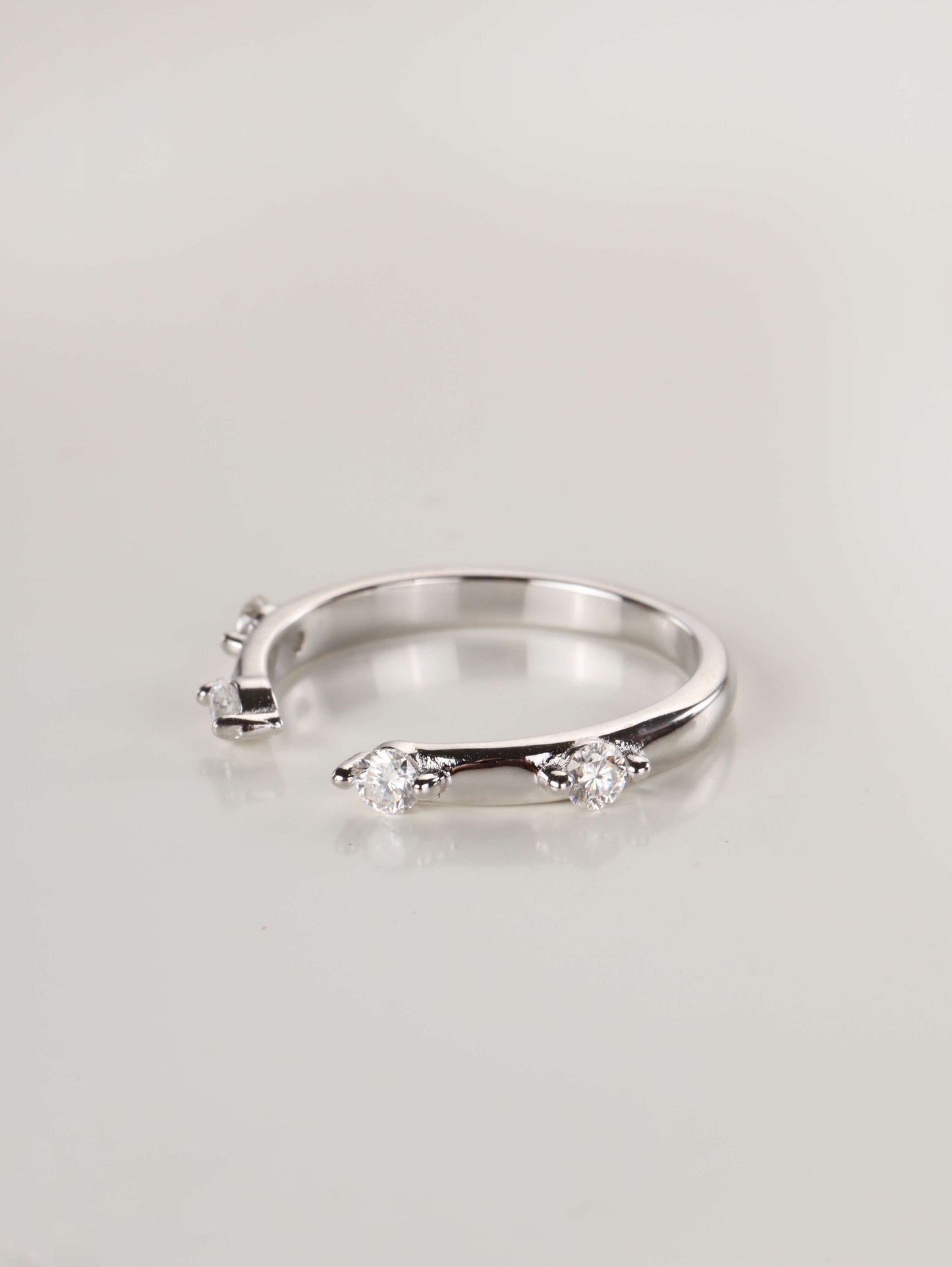 A woman's hand wearing a minimalist silver 0.24ct open cuff ring, showing the spaced moissanite stones framing a centre ring.