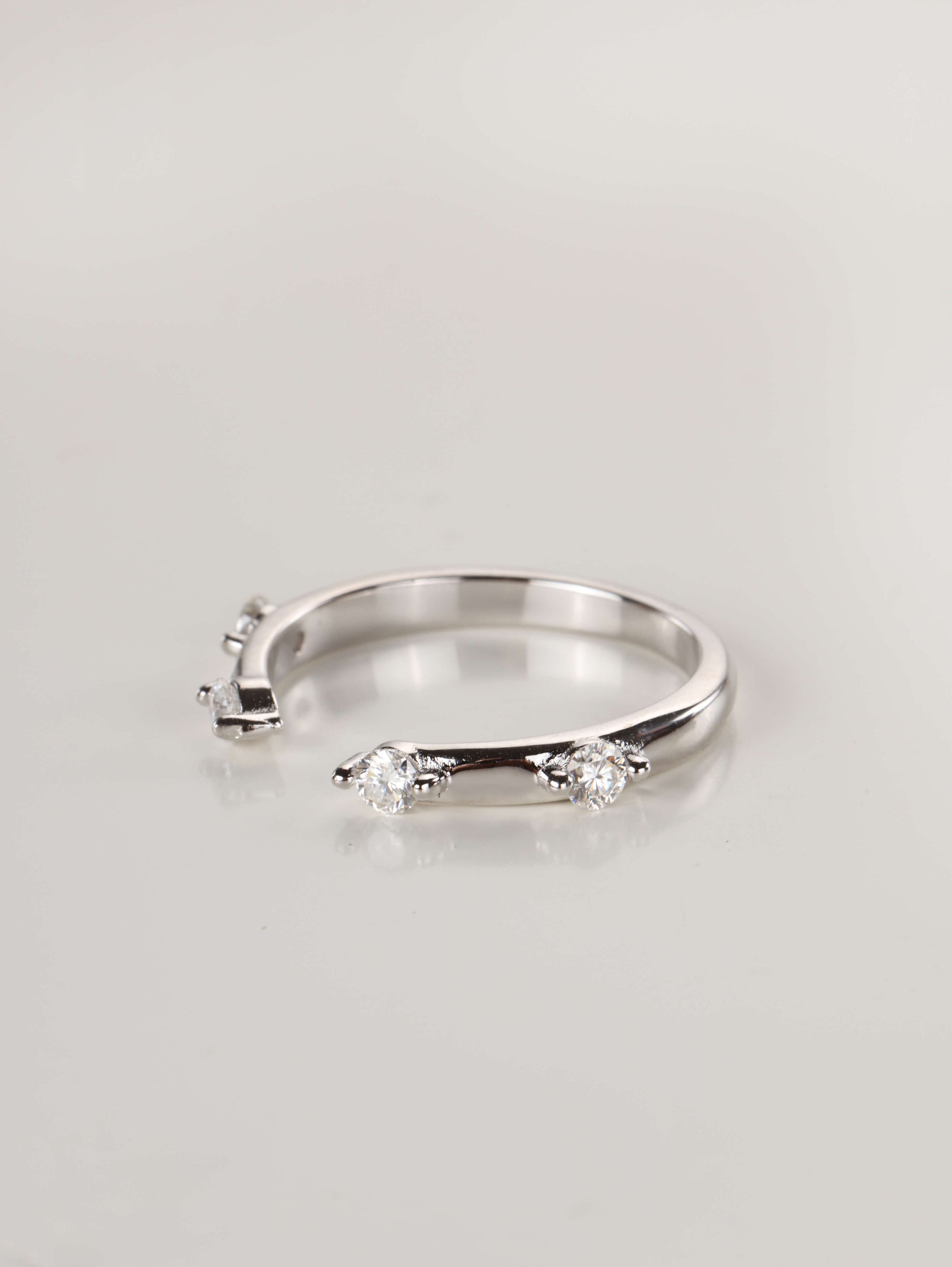 A woman's hand wearing a minimalist silver 0.24ct open cuff ring, showing the spaced moissanite stones framing a centre ring.
