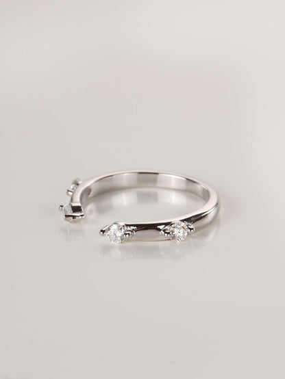 A woman's hand wearing a minimalist silver 0.24ct open cuff ring, showing the spaced moissanite stones framing a centre ring.