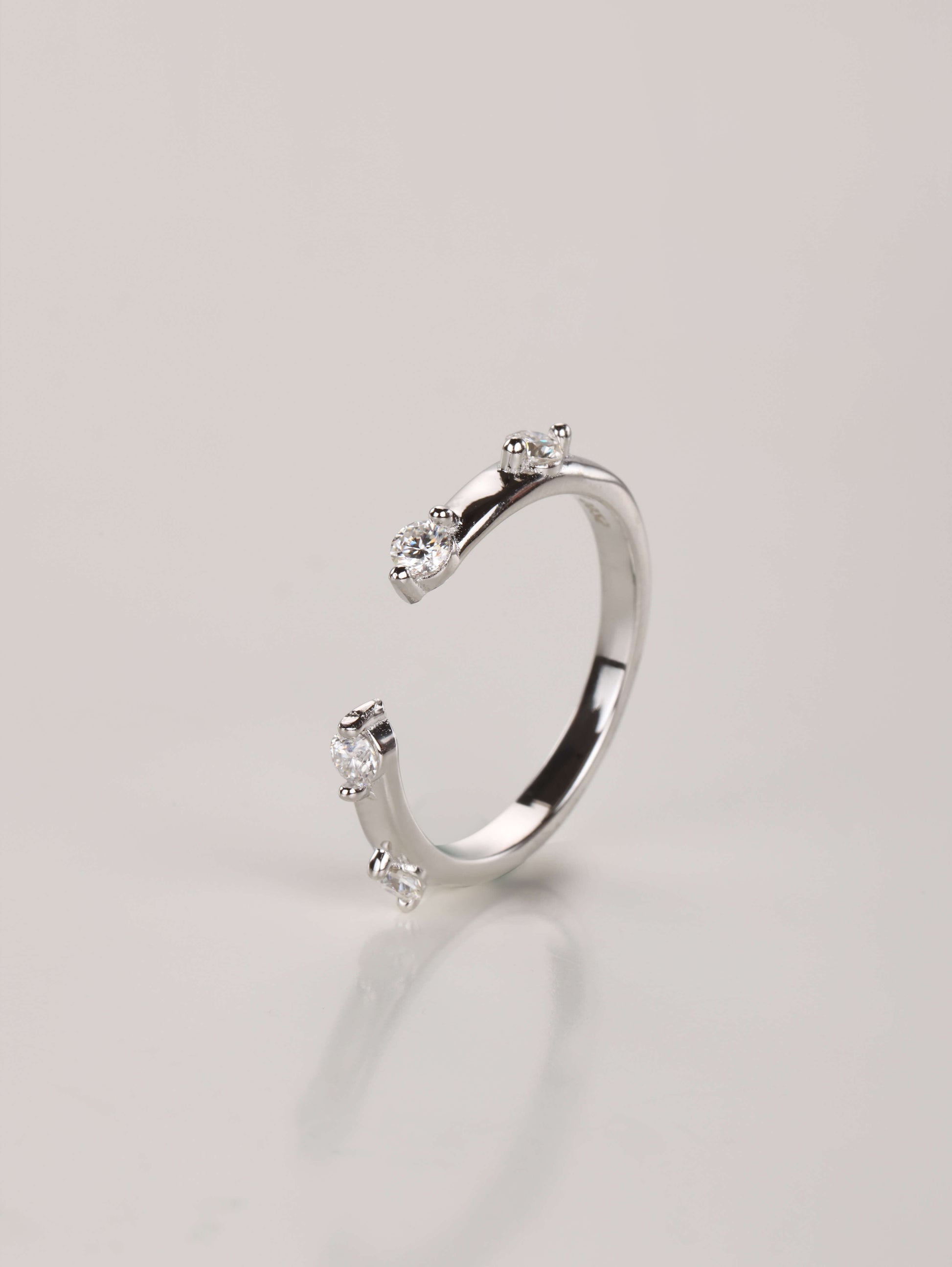 A modern 925 sterling silver stacking ring with a front gap design and delicate spaced stone accents.