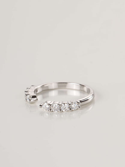 A woman's hand wearing a silver 0.48ct open cuff eternity ring, showing how the gap design perfectly frames the base of an engagement ring.