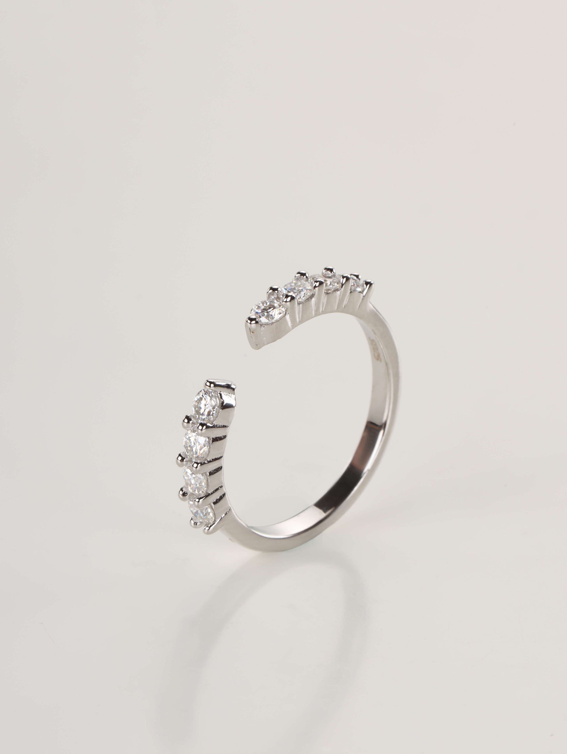 A modern 925 sterling silver stacking ring with an open front design, accented by round brilliant stones.