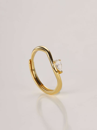 A woman's hand wearing a delicate gold curved ring with a 0.5ct pear-cut moissanite nestled in the wave.