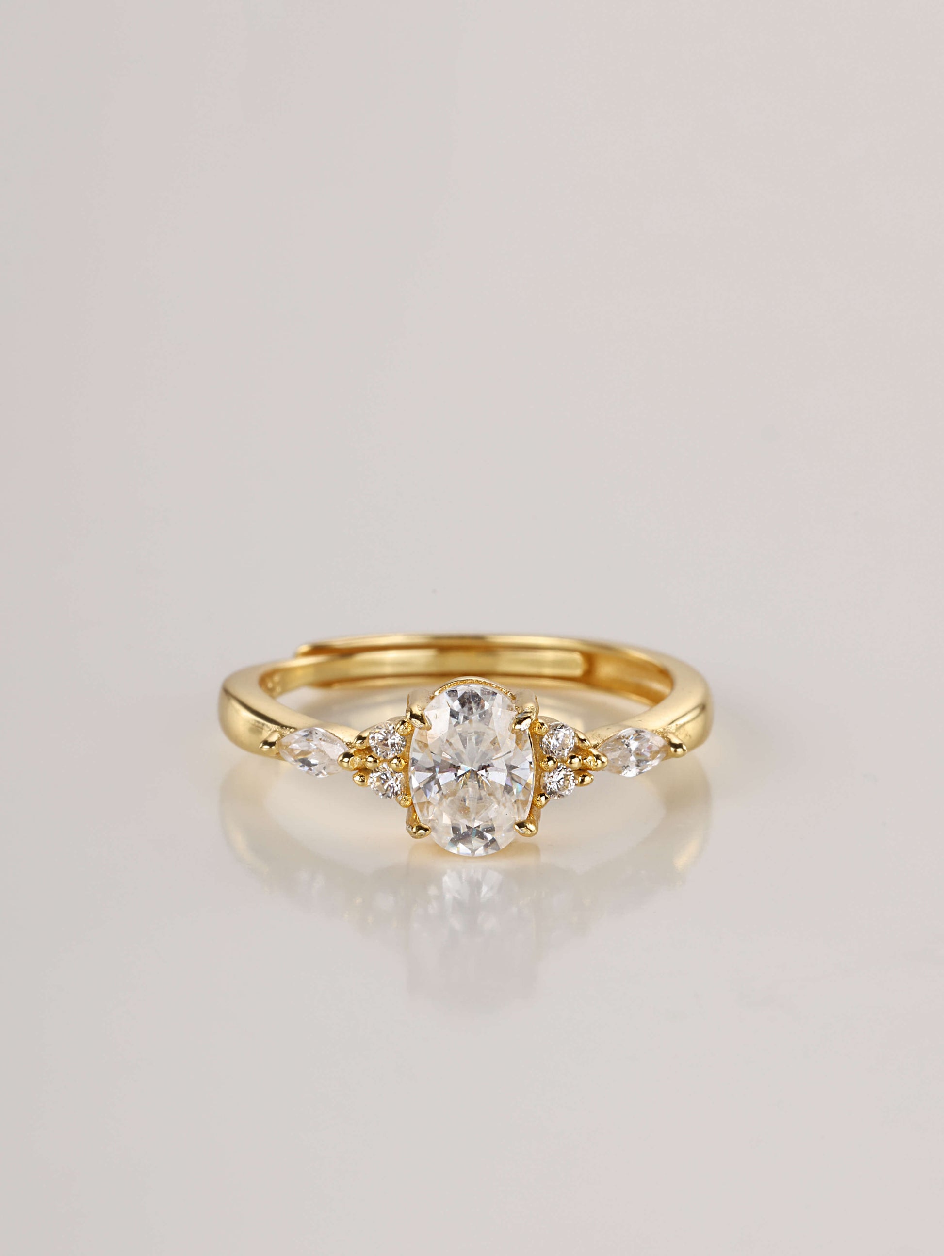 A gold adjustable ring featuring a 1-carat oval moissanite centre stone flanked by marquise and round side stones, set against a clean white background.