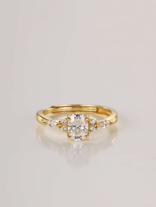 A gold adjustable ring featuring a 1-carat oval moissanite centre stone flanked by marquise and round side stones, set against a clean white background.