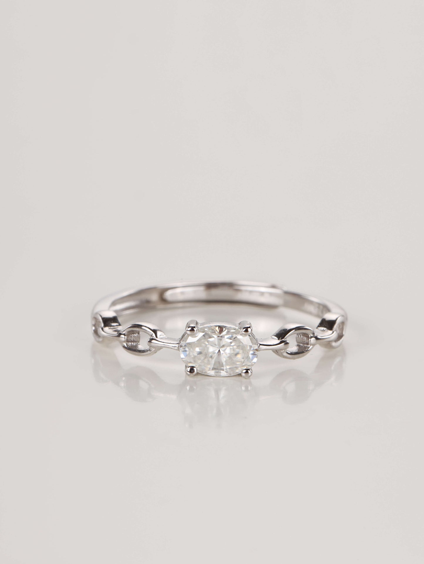 A silver adjustable ring featuring a 0.5-carat oval moissanite centre stone set horizontally on a chain-link style band, resting against a clean white background.