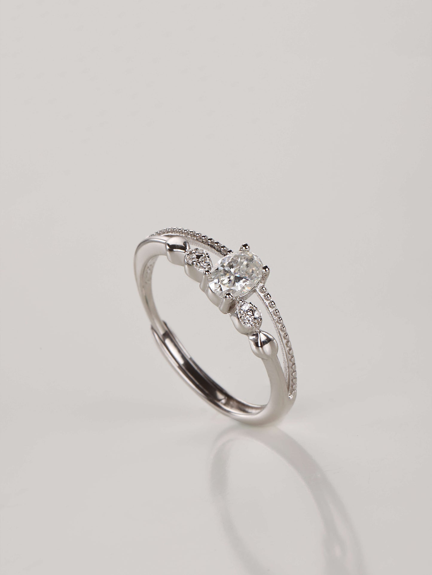 A close-up of a hand wearing the adjustable double layer 0.5ct oval moissanite ring, demonstrating the stacked illusion and sparkle in natural lighting.