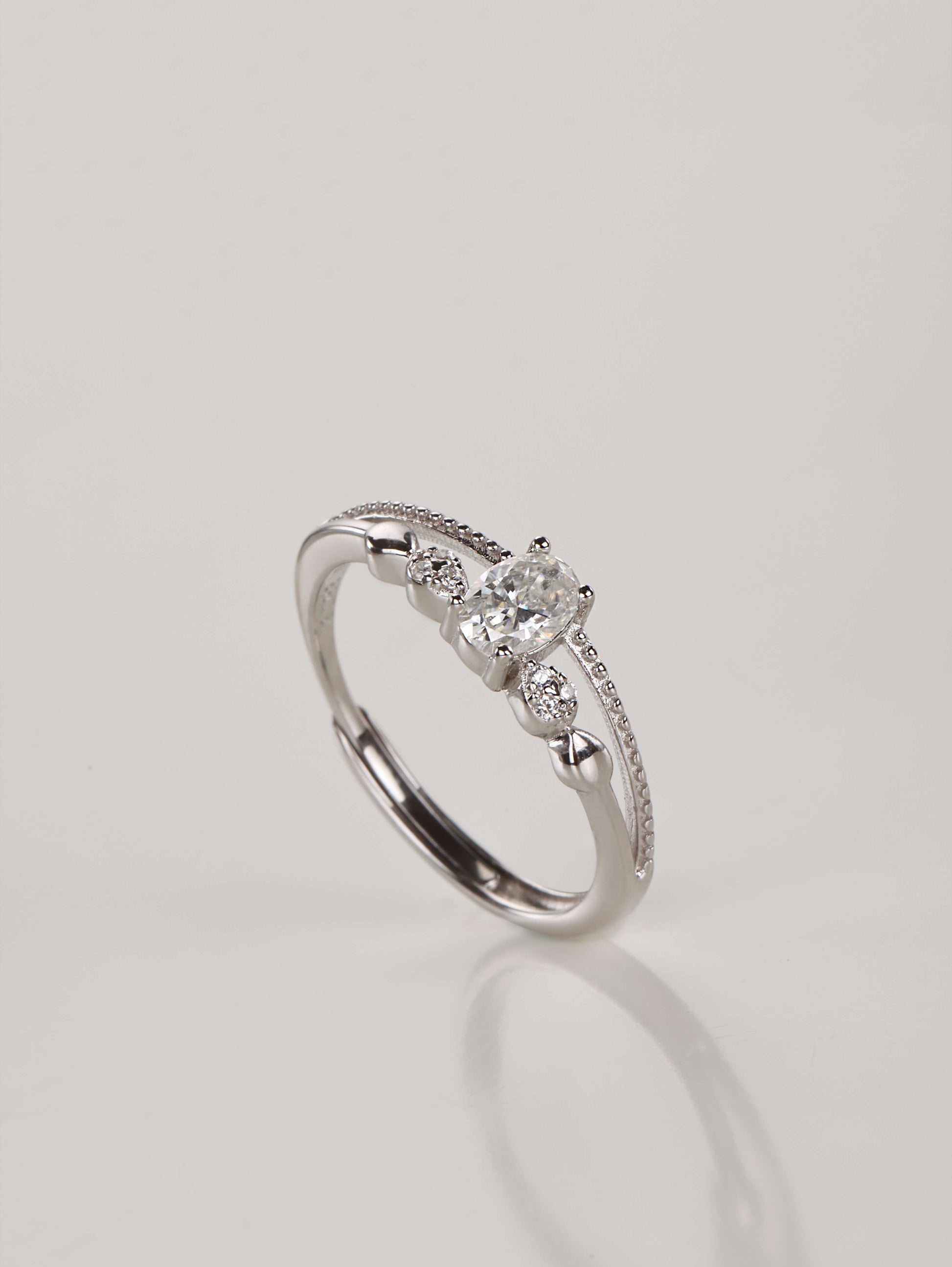 A close-up of a hand wearing the adjustable double layer 0.5ct oval moissanite ring, demonstrating the stacked illusion and sparkle in natural lighting.