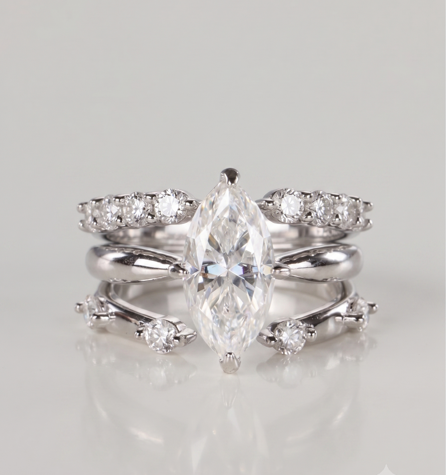 A 3-piece silver moissanite stacking ring set featuring a 2-carat marquise solitaire nested perfectly between an open-front stacker and a gap eternity ring, resting on a clean white background.
