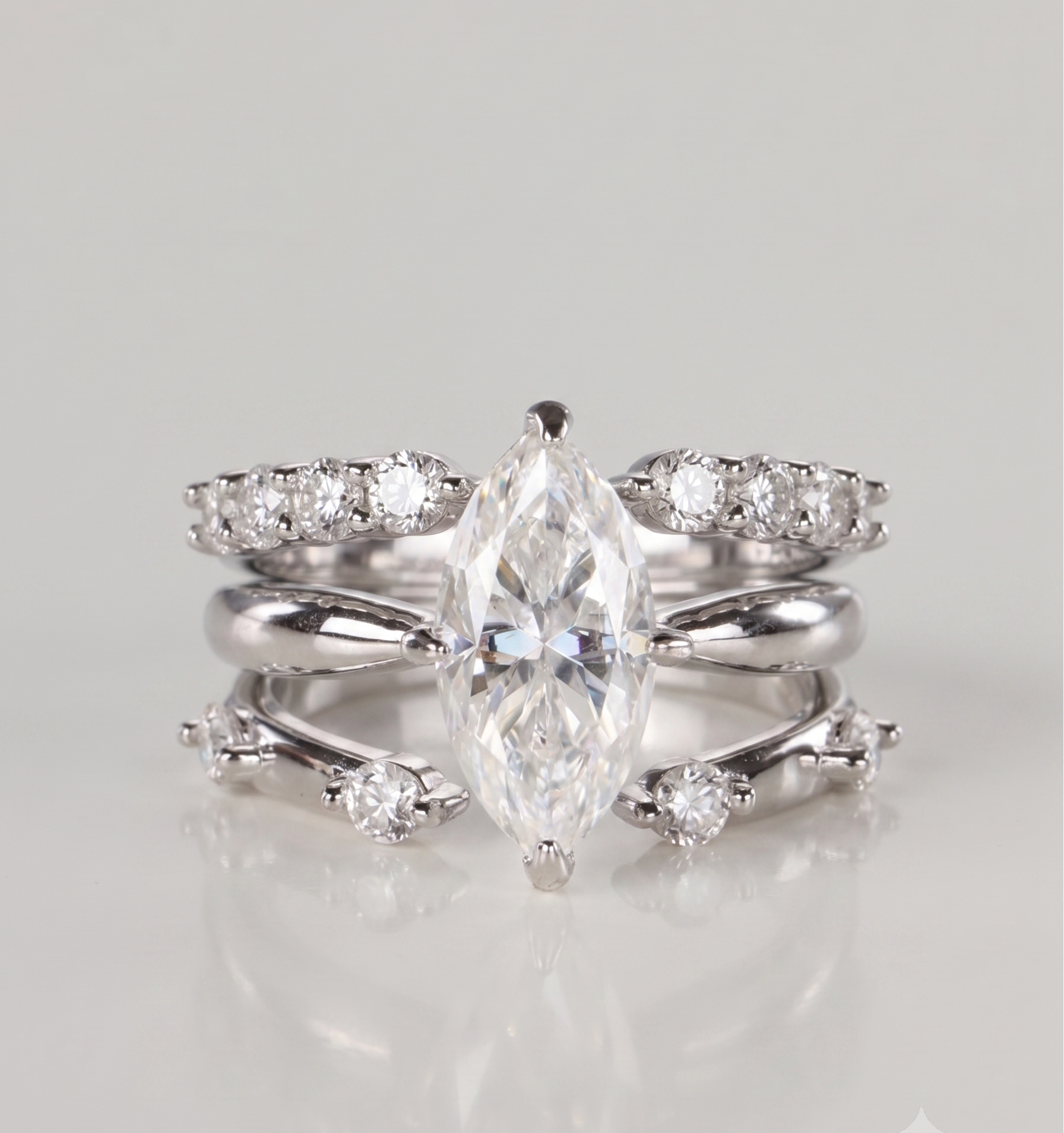 A 3-piece silver moissanite stacking ring set featuring a 2-carat marquise solitaire nested perfectly between an open-front stacker and a gap eternity ring, resting on a clean white background.