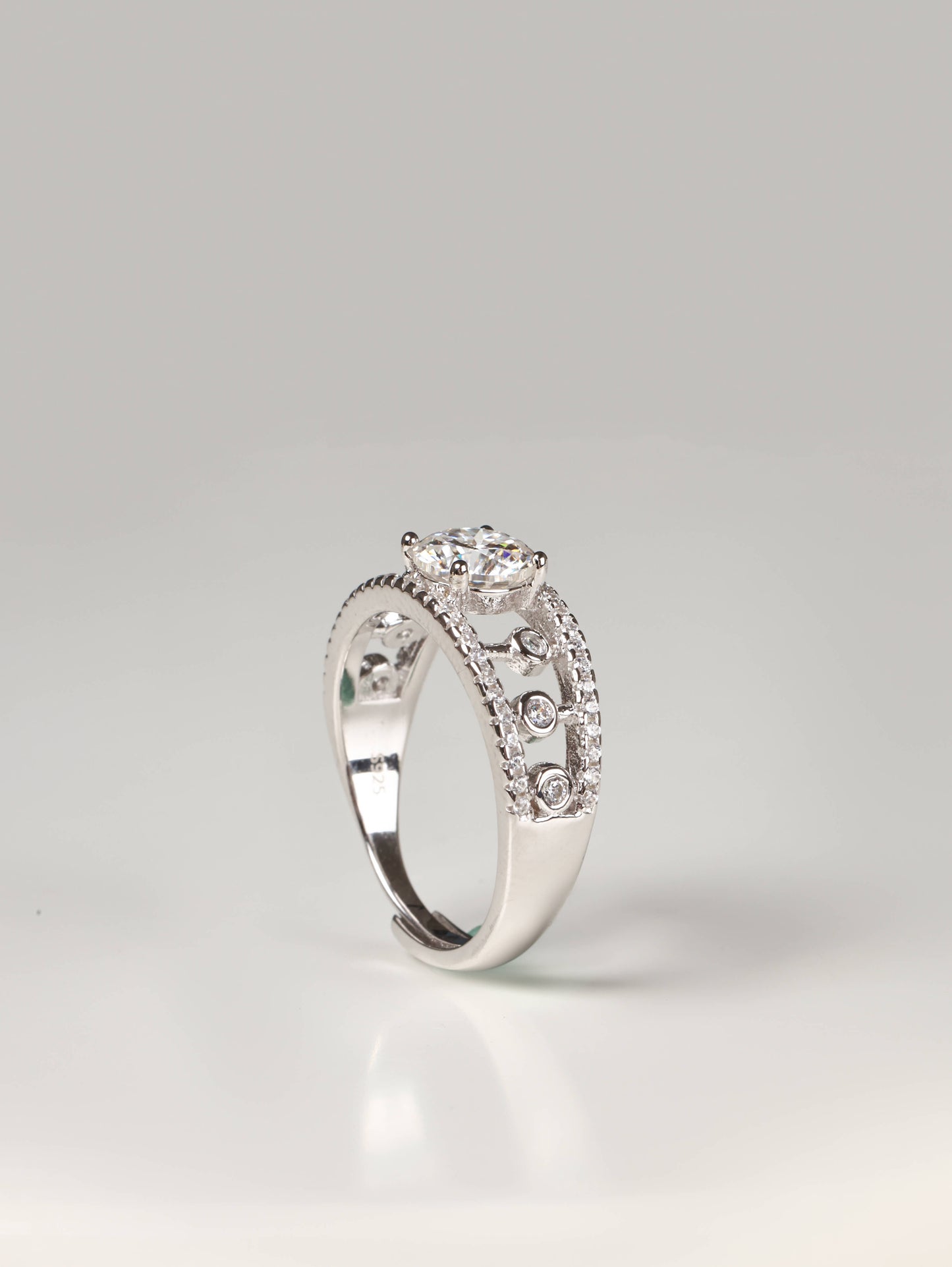 Wide geometric openwork lace ring in silver with a round solitaire gemstone worn on a finger