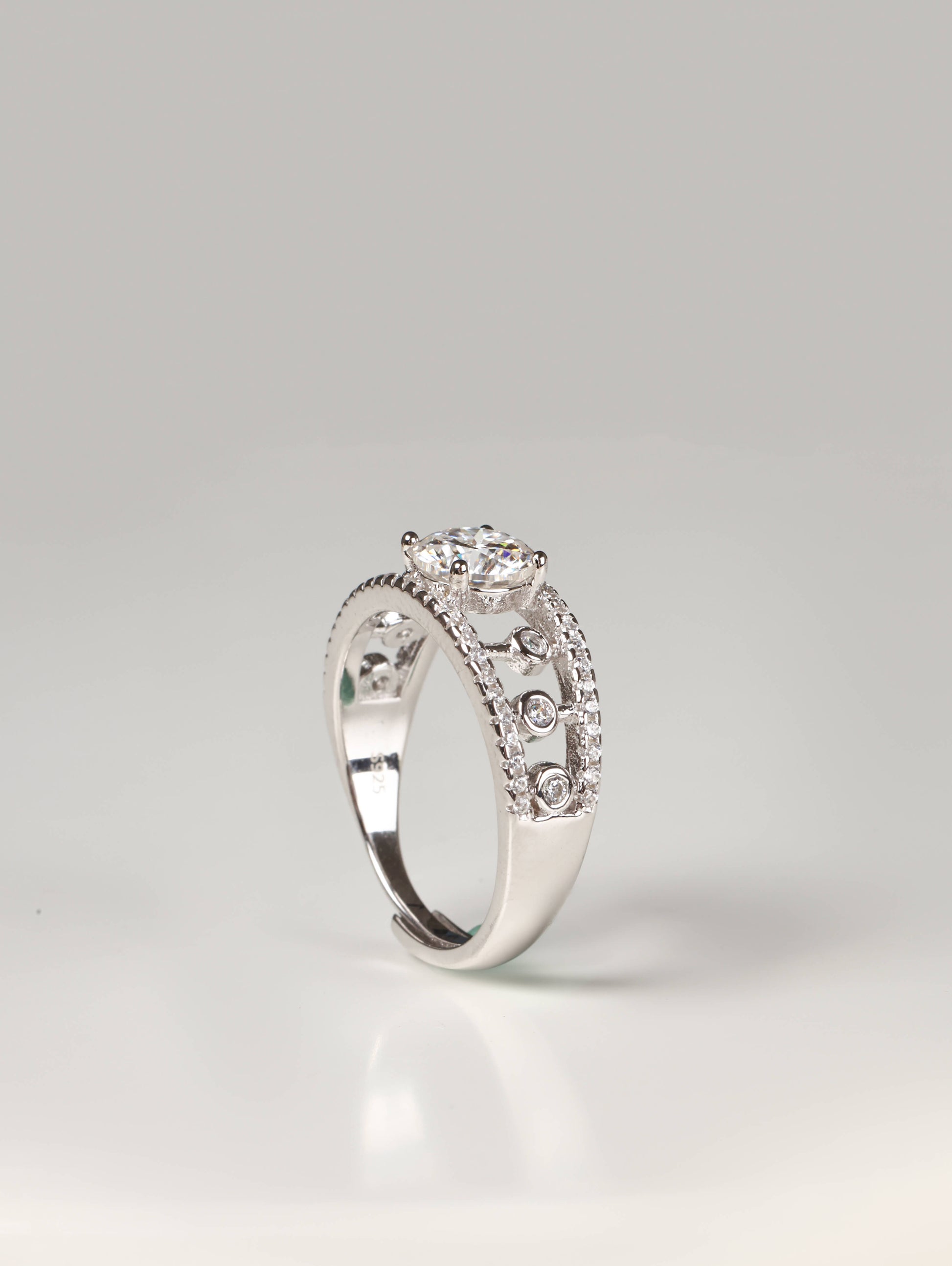 Wide geometric openwork lace ring in silver with a round solitaire gemstone worn on a finger