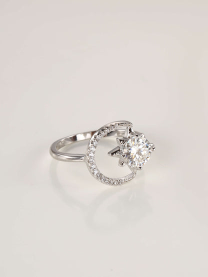 Close-up macro shot of the silver celestial moon and star ring, highlighting the brilliant moissanite centre stone and delicate pavé moon accents.