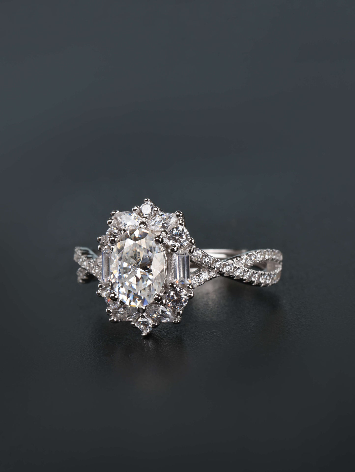 Vintage style oval engagement ring with a mosaic starburst halo and intertwined pavé band on a finger