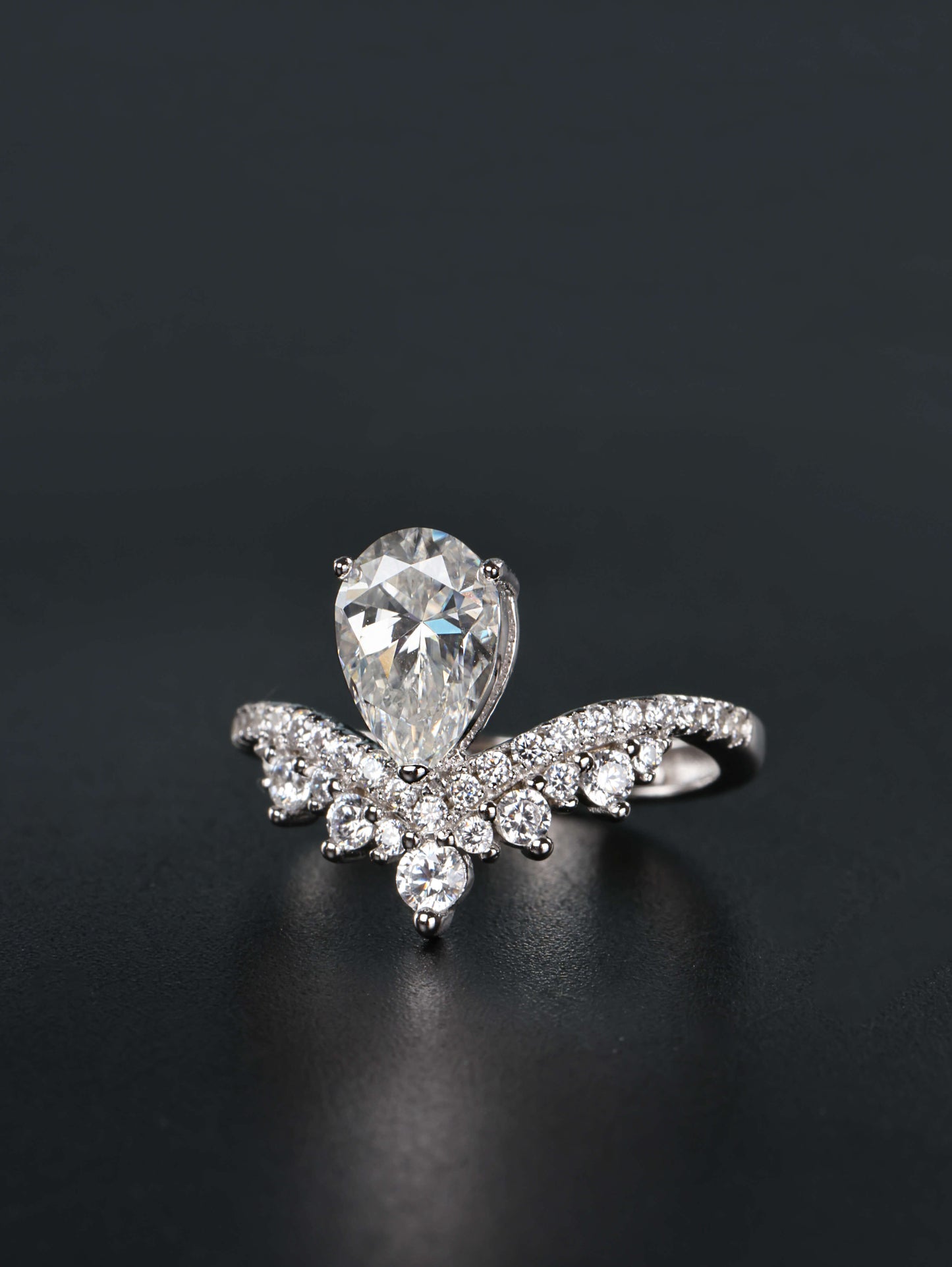 Alternative pear shaped moissanite engagement ring with a chevron tiara crown worn on a finger
