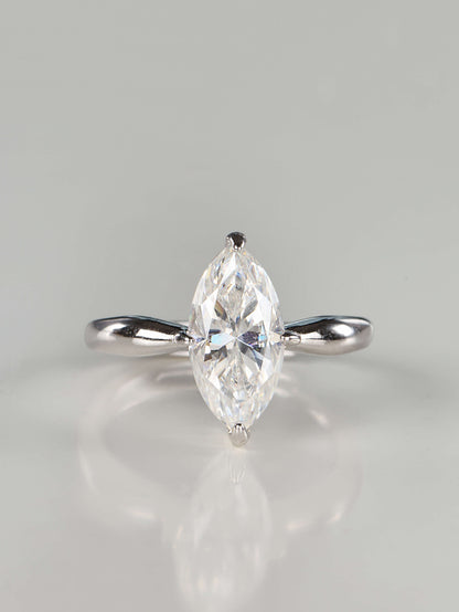 Close up of a brilliant marquise cut moissanite solitaire ring set in 925 sterling silver, featuring a tapered polished band and secure V-prongs, resting on a clean white background.