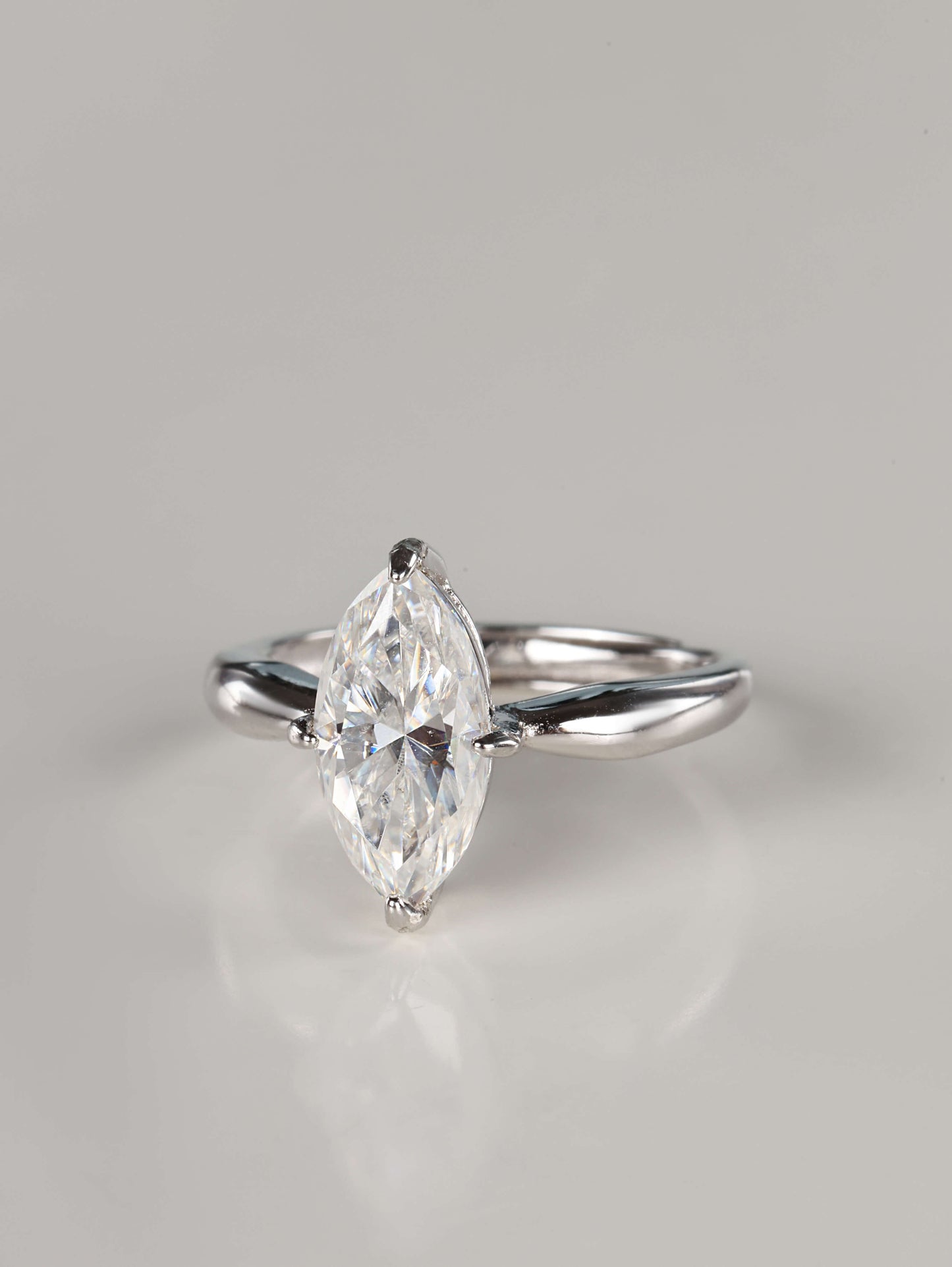 A direct front view of a 2ct moissanite marquise ring. The image emphasizes the unique 'boat' shape of the marquise stone and the protective V-shaped claw settings on the delicate pointed tips. It features a sleek, plain polished silver band that tapers toward the centre gem.