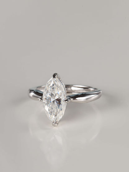 A direct front view of a 2ct moissanite marquise ring. The image emphasizes the unique 'boat' shape of the marquise stone and the protective V-shaped claw settings on the delicate pointed tips. It features a sleek, plain polished silver band that tapers toward the centre gem.