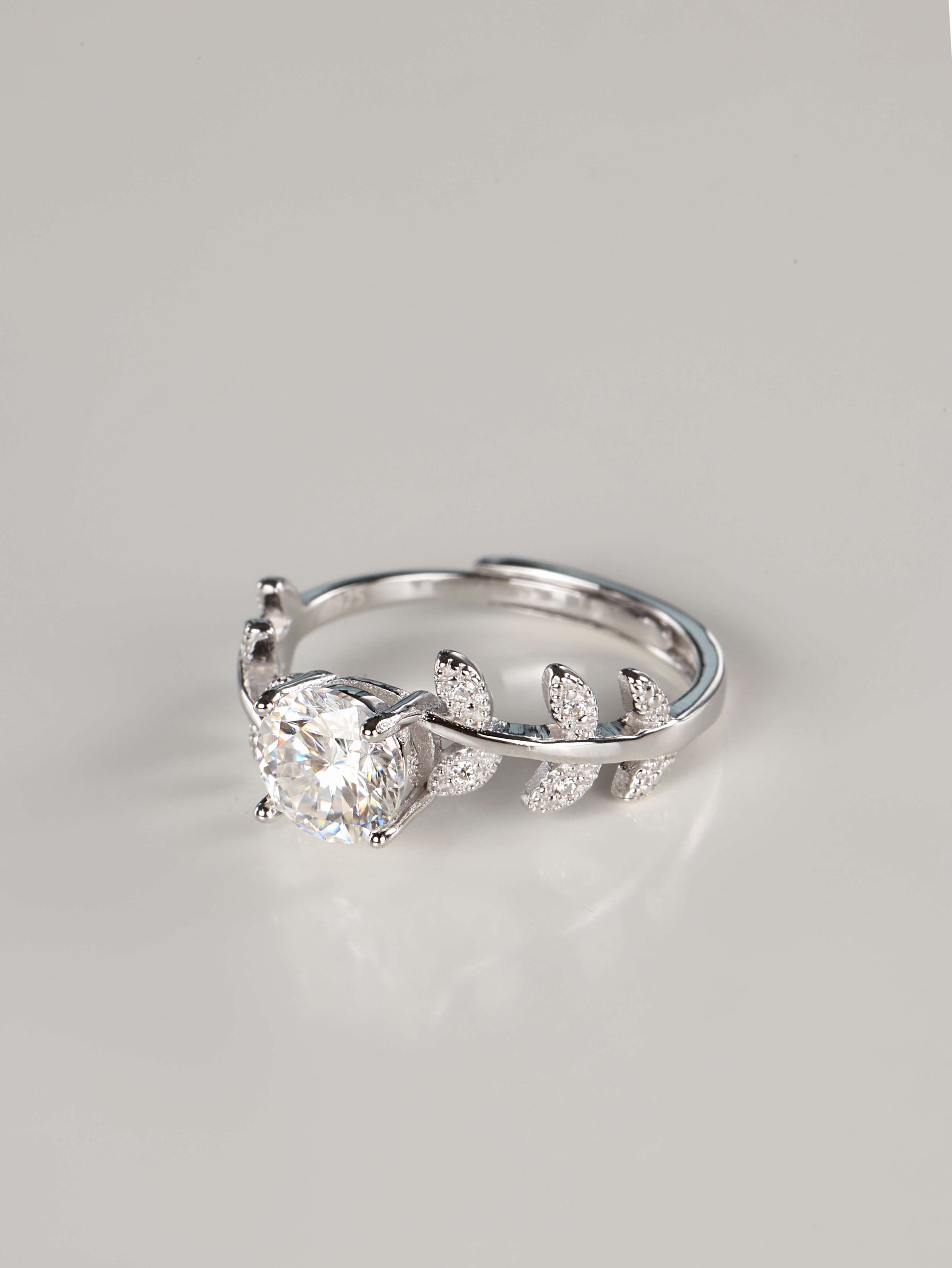 Close up of a woman wearing a 1 carat botanical moissanite engagement ring on her index finger