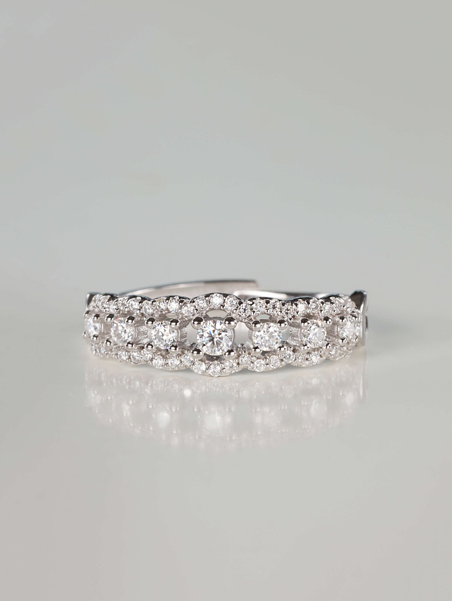 Close-up of a 0.41ct vintage-inspired silver lace eternity ring featuring a central row of brilliant moissanite stones bordered by scalloped pavé edges, resting on a clean reflective surface.