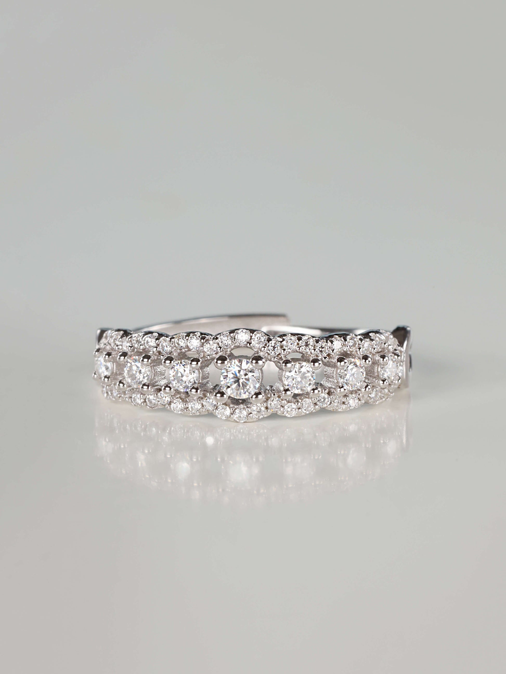 Close-up of a 0.41ct vintage-inspired silver lace eternity ring featuring a central row of brilliant moissanite stones bordered by scalloped pavé edges, resting on a clean reflective surface.