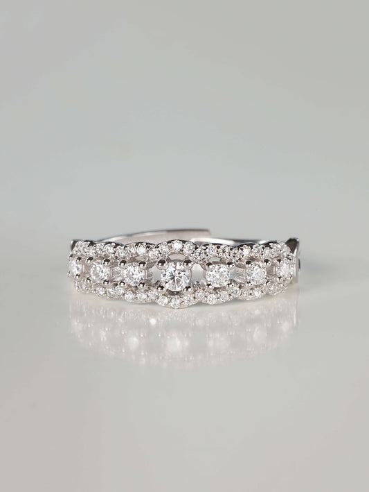 Close-up of a 0.41ct vintage-inspired silver lace eternity ring featuring a central row of brilliant moissanite stones bordered by scalloped pavé edges, resting on a clean reflective surface.