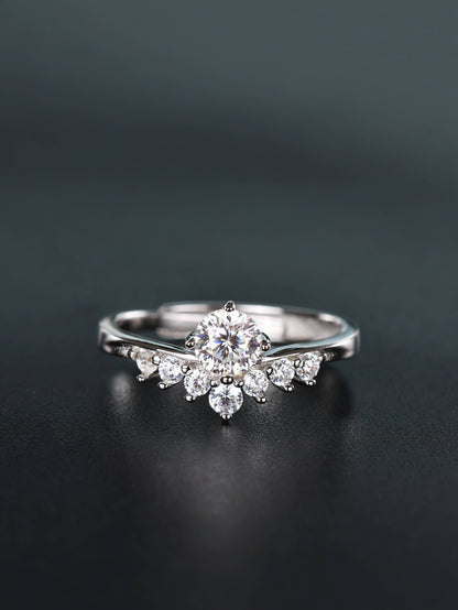 Close-up of a silver 0.5ct V-shape moissanite ring resting on a dark surface, featuring a brilliant round centre stone nestled inside a curved band with smaller pavé diamonds.