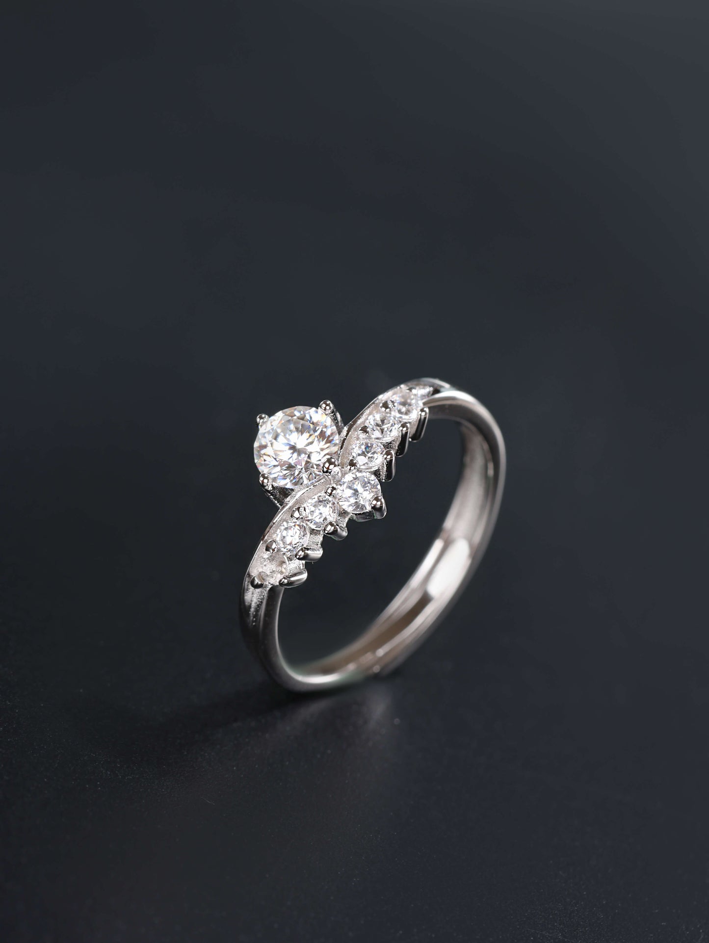 A profile angle of a silver V-shape stacking ring, showcasing the 0.5ct moissanite centre stone and the discrete open-back adjustable band design.