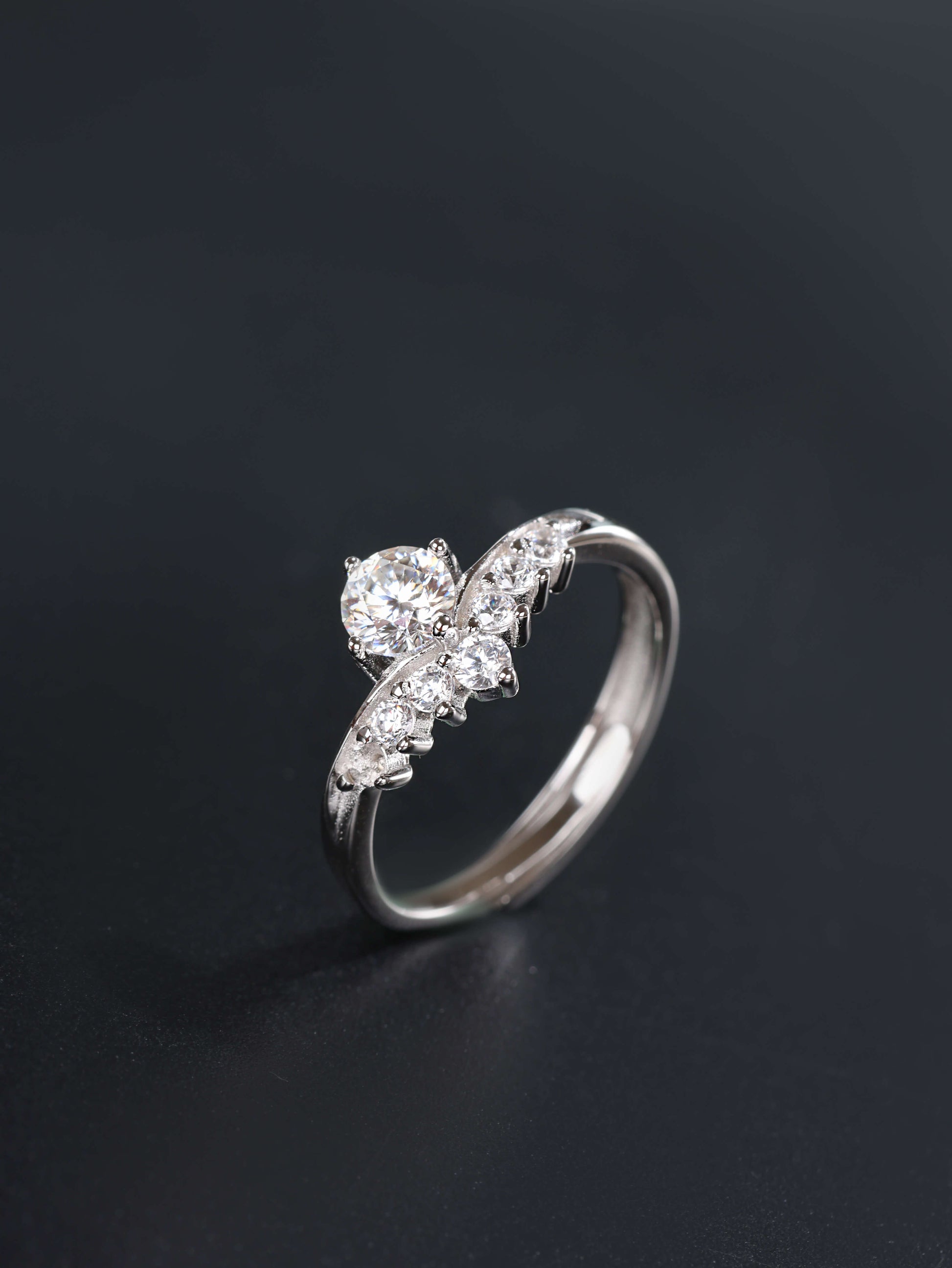 A profile angle of a silver V-shape stacking ring, showcasing the 0.5ct moissanite centre stone and the discrete open-back adjustable band design.