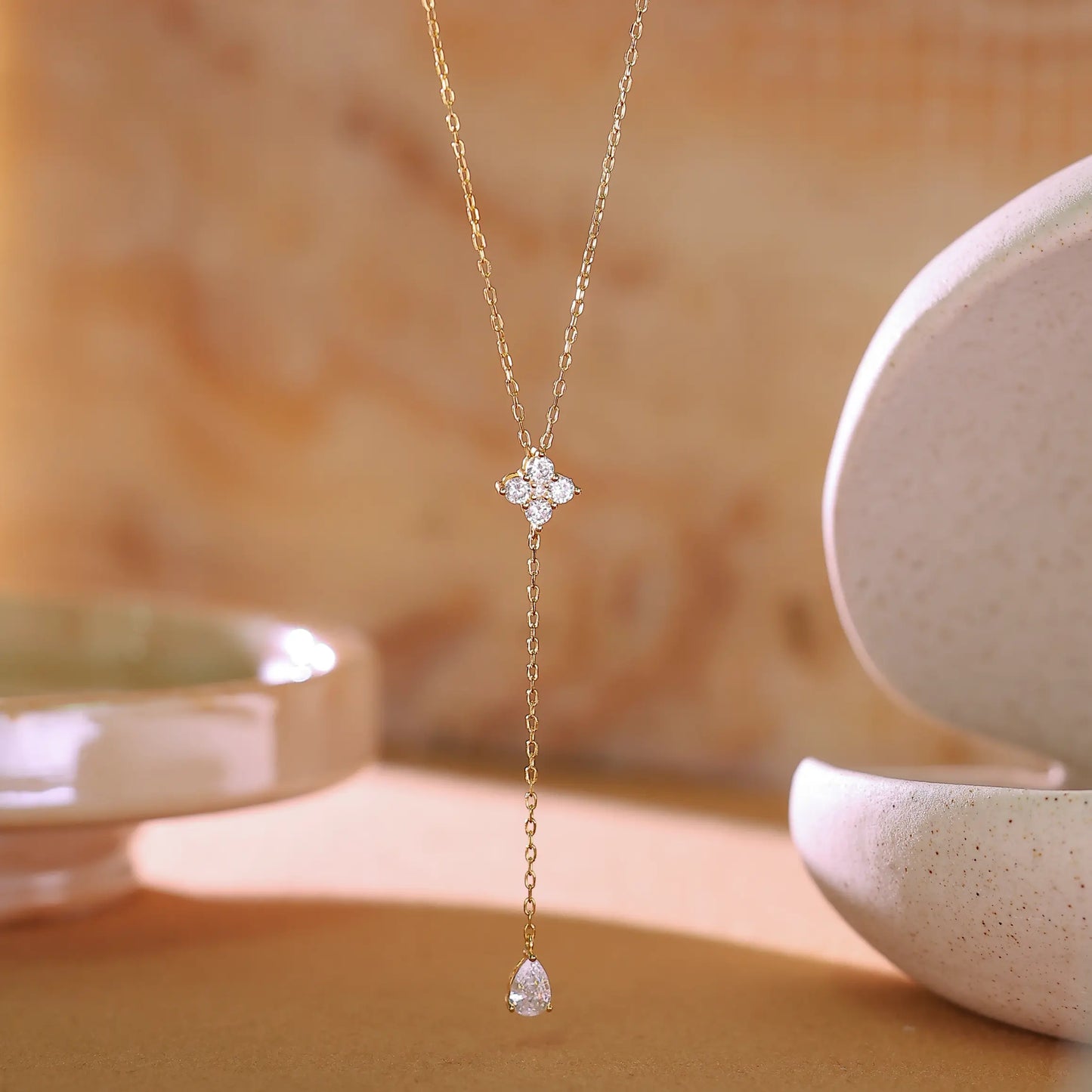 Macro shot of cubic zirconia flower cluster setting on gold lariat necklace