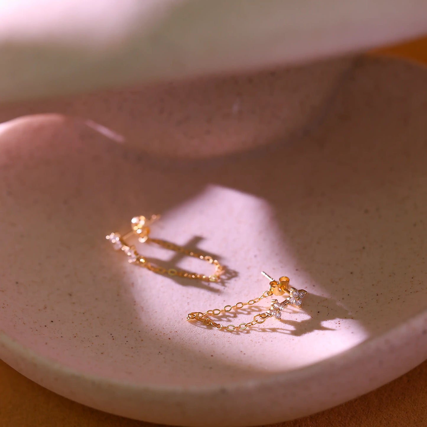 Close up of the delicate gold cable chain dangling from the flower stud.