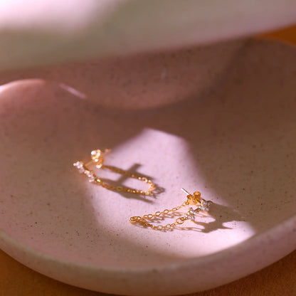 Close up of the delicate gold cable chain dangling from the flower stud.