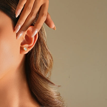 Close up of oval solitaire earrings on a model, showing the elongated shape.