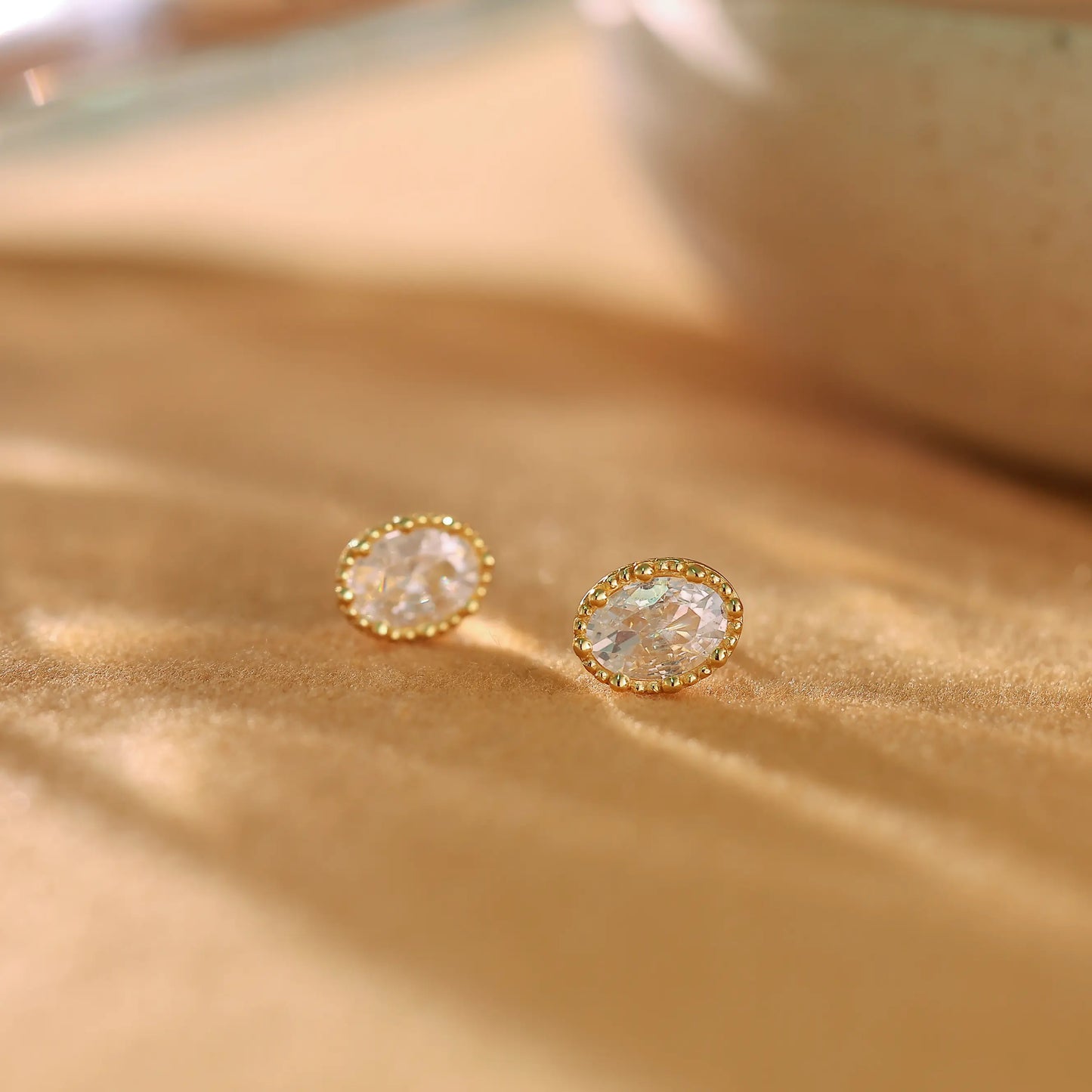 Pair of 14K gold plated sterling silver stud earrings with oval cubic zirconia stones.
