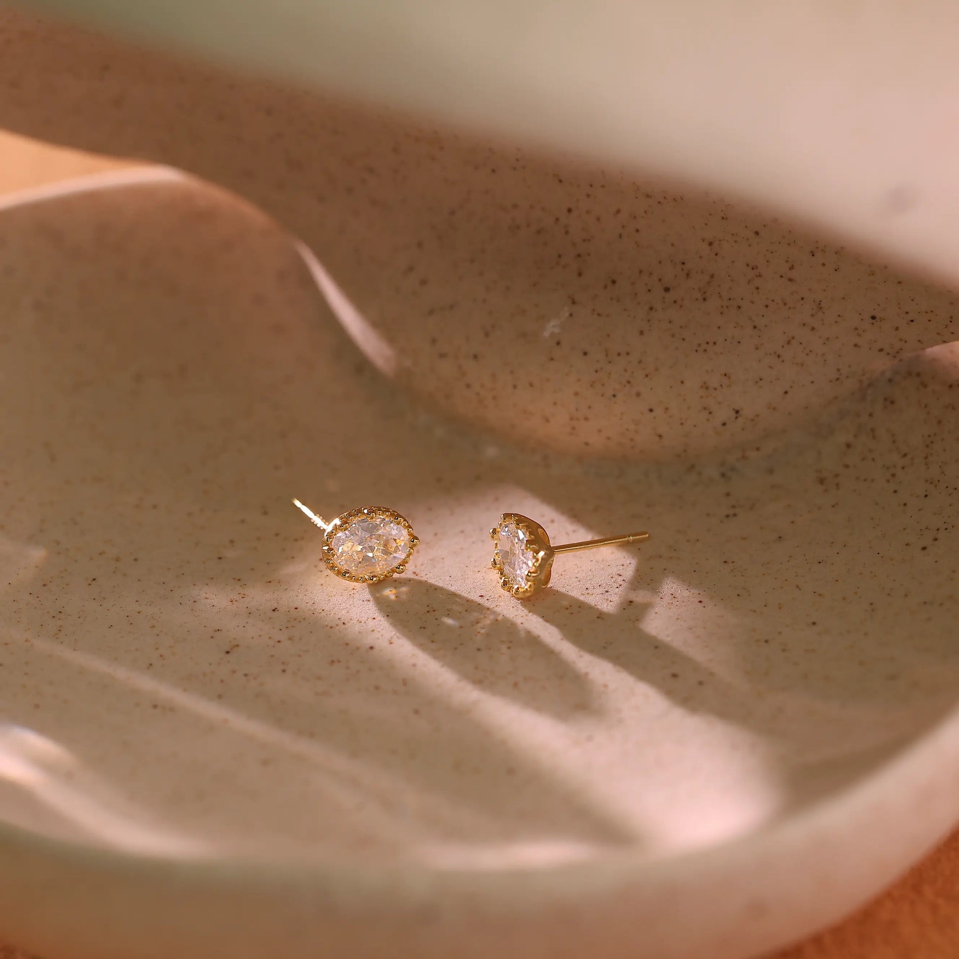 Side view of the gold stud earring showing the setting height and post.
