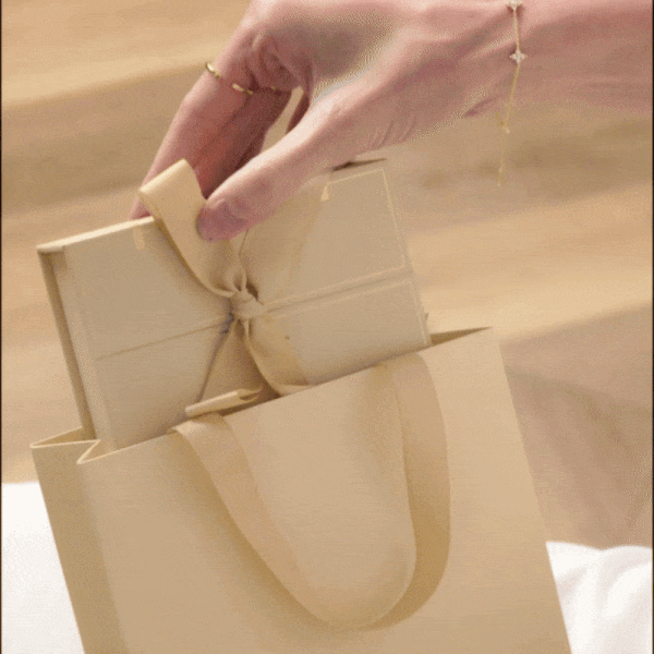 Video showing the full unboxing experience: hands slowly untying the satin ribbon, lifting the lid, and revealing the sparkling jewellery inside.